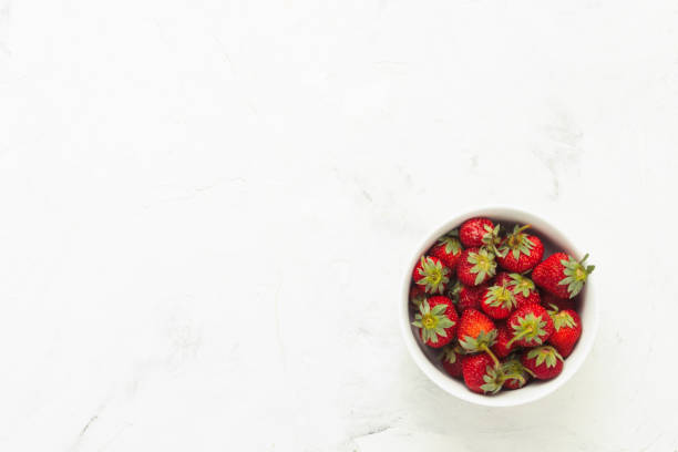 istock White plate with strawberries on a light stone background. Flat 1195643105