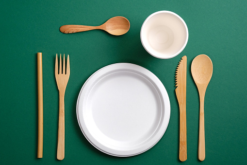 Set of Eco friendly bamboo cutlery on green background. Flat lay composition with reusable kitchenware. Zero waste, plastic free concept. Sustainable lifestyle