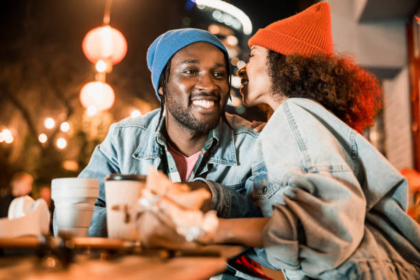 istock Pretty smiling girl saying something in guy ear 1195648064