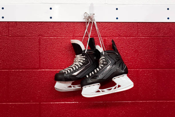 hockey skates hanging over red wall with copy space - ice hockey ice ice skating sport imagens e fotografias de stock