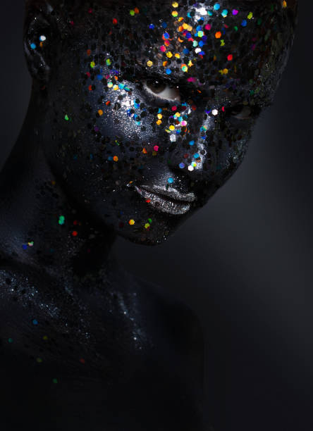 istock creative female portrait. face in black paint with large sequins 1195652283