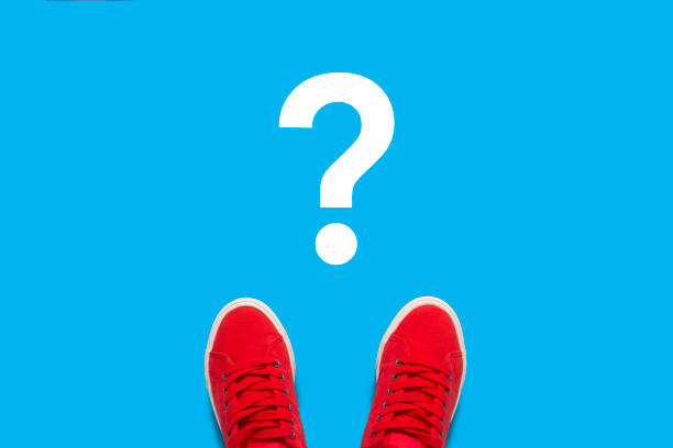 istock Legs in red sneakers standing on a blue background with a questi 1195652569
