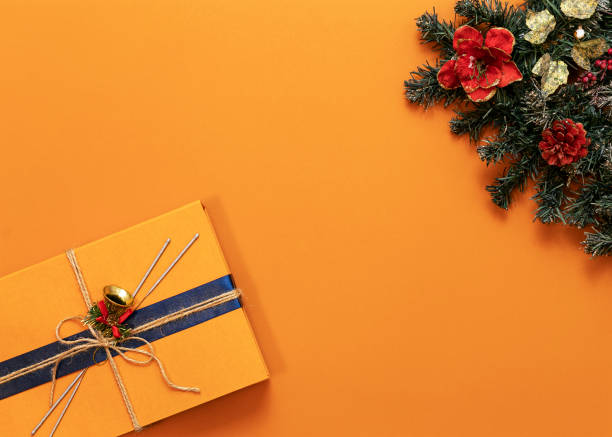 istock bright orange background, green tree in the upper right corner, orange gift box in the lower left corner 1195653640