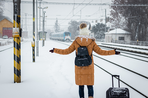 Tourist looking at leaving train at railway station. Traveling in winter