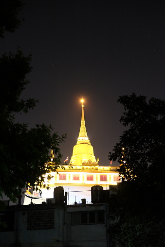 The spire of Wat Saket Temple is lit at night.