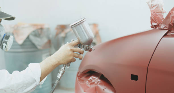 travailleur de mécanicien automatique de réparation de voiture peignant une voiture dedans avec le corps de voiture de peinture de pulvérisation d'aérographe dans la chambre de peinture - airbrush machine airbrushing paint photos et images de collection