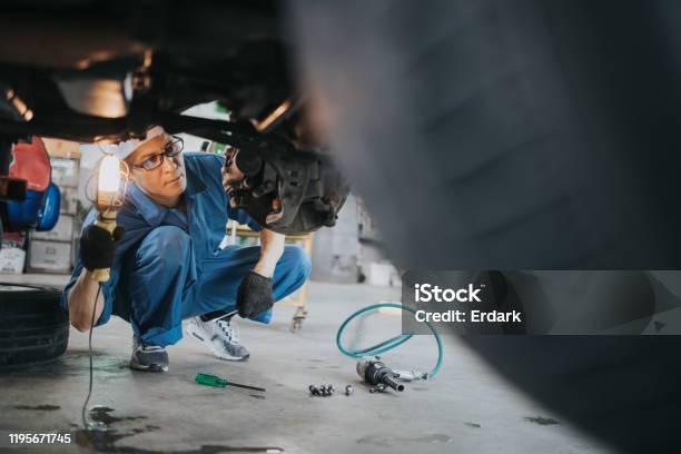 Thai Mechanic Man With Lamp Working At Car Auto Repair Shop Stock Photo Stock Photo - Download Image Now