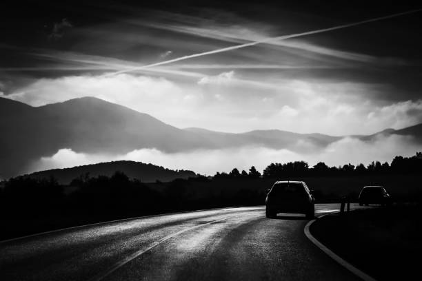 Rear view of two cars driving on the two way road with landscape of Gorski Kotar in Croatia, in black and white.
