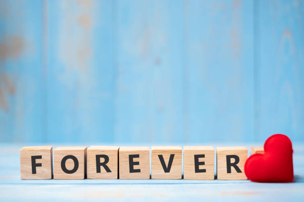 istock FOREVER wooden cubes with red heart shape decoration on blue table background and copy space for text. Love, Romantic and Happy Valentine