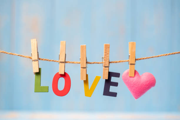 istock LOVE text and pink heart shape decoration hanging on line with copy space for text on blue wooden background. Love, Wedding, Romantic and Happy Valentine