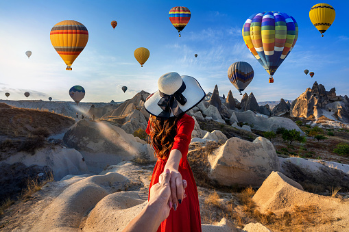 Mujeres turistas sosteniendo la mano del hombre y llevándolo a globos aerostáticos en Capadocia, Turquía. photo