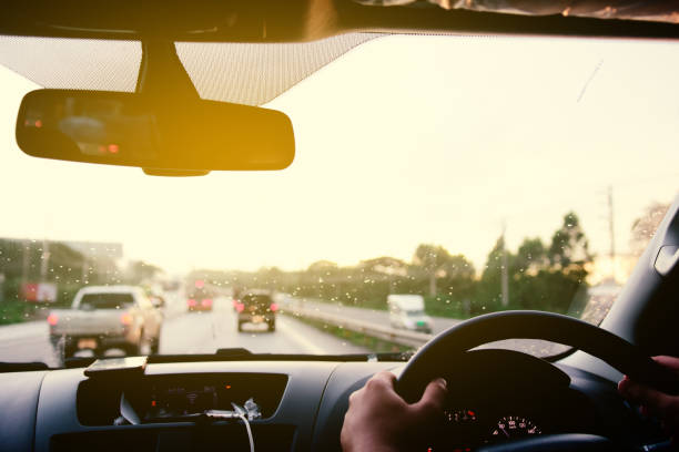istock Man driving car from rear view on the highway With sunlight. 1195684126