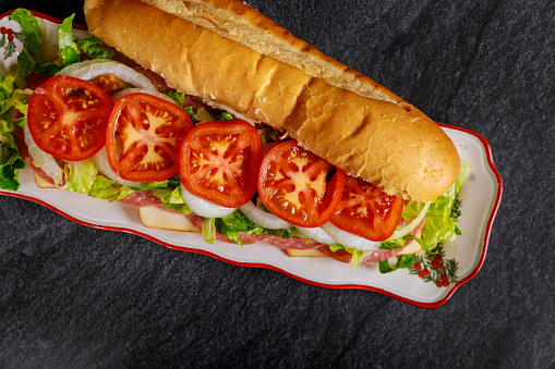 Long delicious sub with muenster cheese, salami, and vegetable.