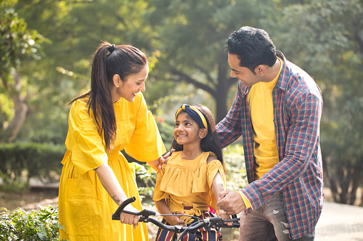 Girl learning to ride a bicycle with her parent in park