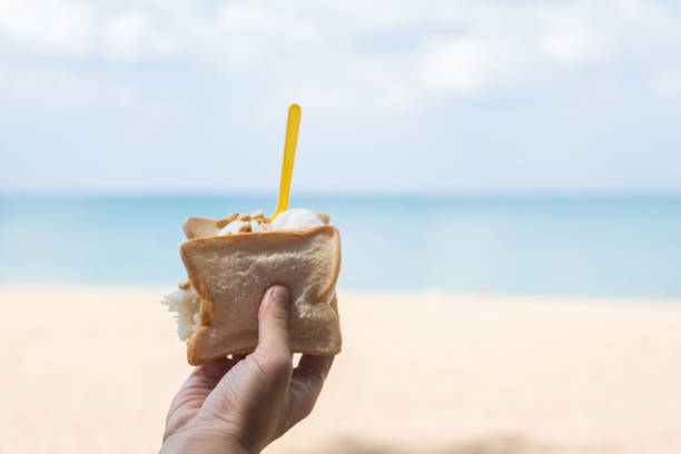 istock One hand holds tasty ice cream on a summer beach. 1195696966