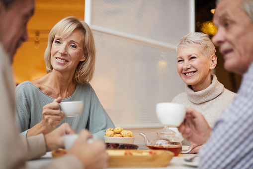 Smiling mature friends chatting over tea cup