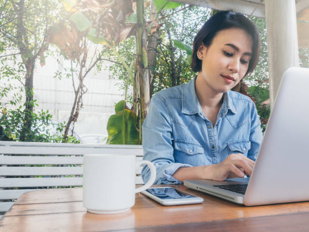 istock Beautiful happy asian woman using laptop computer in cafe. 1195700772