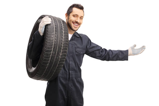 istock Auto mechanic with a tire gesturing welcome with hand 1195705921