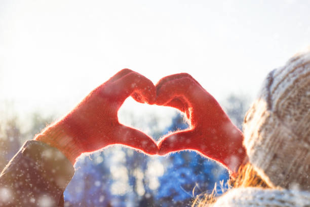 istock Women's Hands in Red Glove Folded in Heart Shape. Winter Concept. Snowfall 1195710975