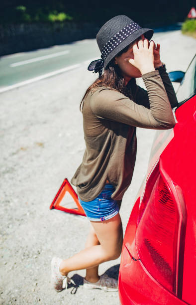 istock Woman standing by a broken down car 1195718264