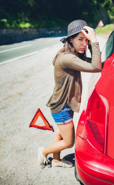 istock Woman standing by a broken down car 1195718282
