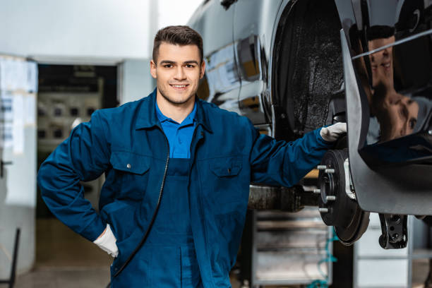 istock smiling mechanic looking at camera while touching disc brakes of car 1195719249