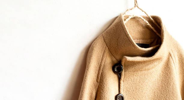 istock beige wool coat hanging on clothes hanger on white background. 1195727216