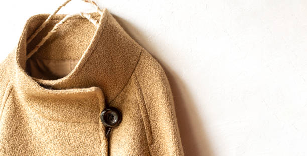 istock beige wool coat hanging on clothes hanger on white background. 1195727531