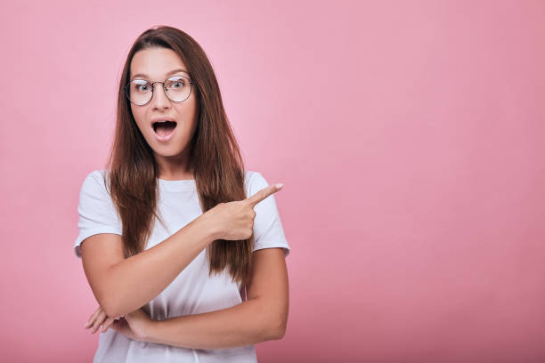 istock Cute lady shows forefingers to the side and her mouse open 1195728348