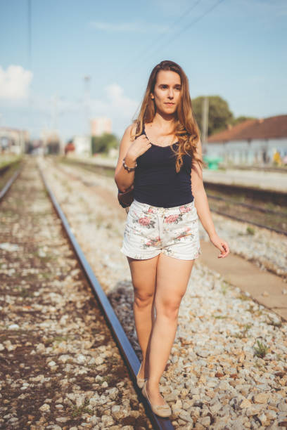 Young woman walking down railroad tracks.