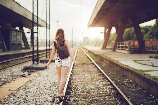 Young woman walking down railroad tracks.