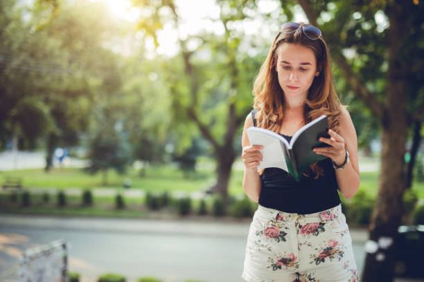 istock Woman student reading book downtown 1195729195