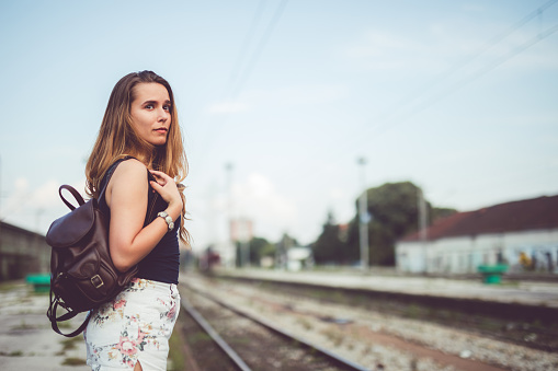 Young woman waiting for the train at the railroad station.