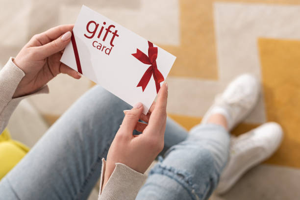 vista recortada de la chica sosteniendo la tarjeta de regalo con arco rojo - vale de regalo fotografías e imágenes de stock