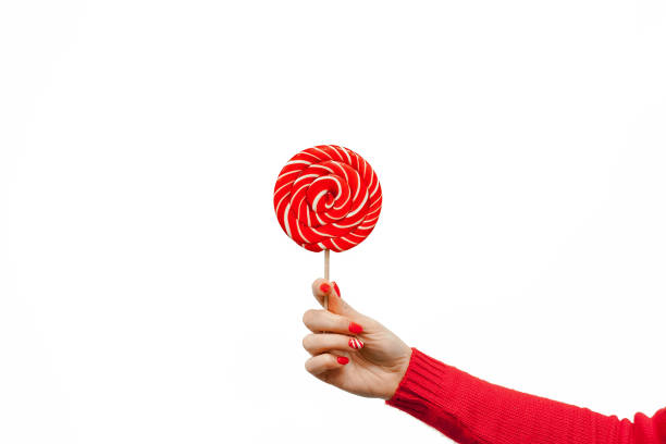 czerwony i biały lizak spiralny u kobiet ręcznie wyizolowany na białym tle - stick of hard candy candy vibrant color multi colored zdjęcia i obrazy z banku zdjęć