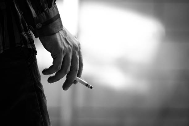 istock man holding smoking a cigarette in hand. Cigarette smoke spread 1195740213