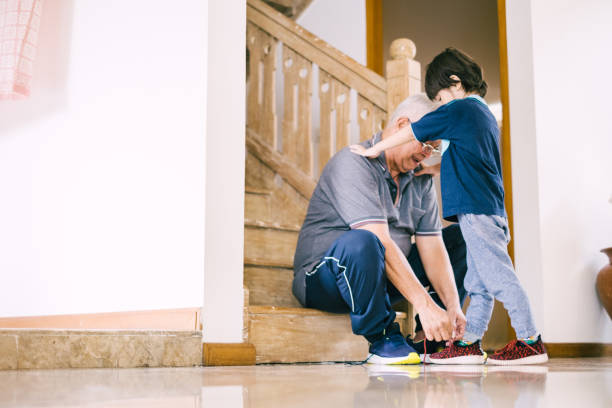 istock Grandfather Helping Grandson Tying Shoe Lace 1195740251