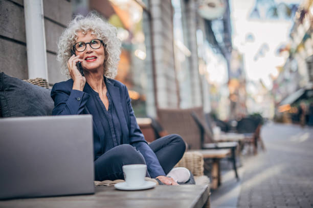 istock Old lady talking on mobile outdoors in cafe 1195743442