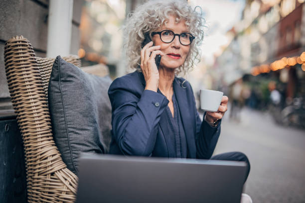 istock Old lady talking on mobile outdoors in cafe 1195743552