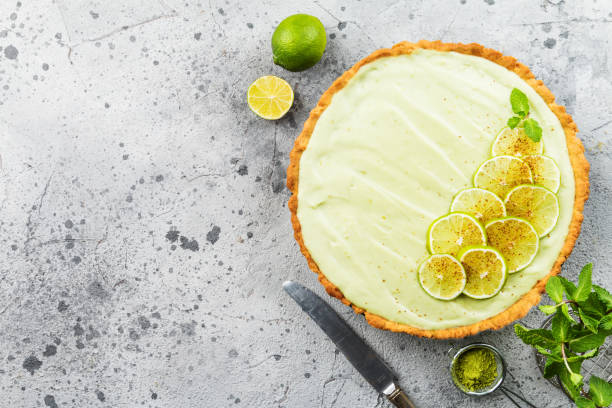 Key Lime Pie Key Lime Pie with several limes and mint over gray background, top view with copy space. florida food stock pictures, royalty-free photos & images