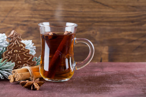 istock Winter hot tea with cinnamon, anise, chocolate shaped christmas tree and christmas tree branch on wood brown background. 1195748016