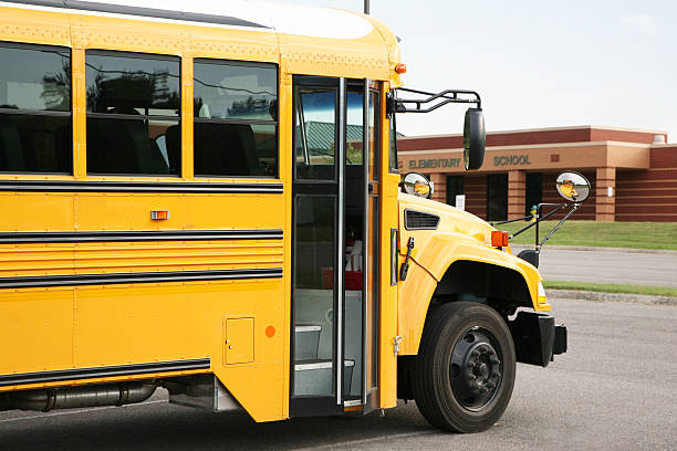 Yellow bus in front of a school stock photo