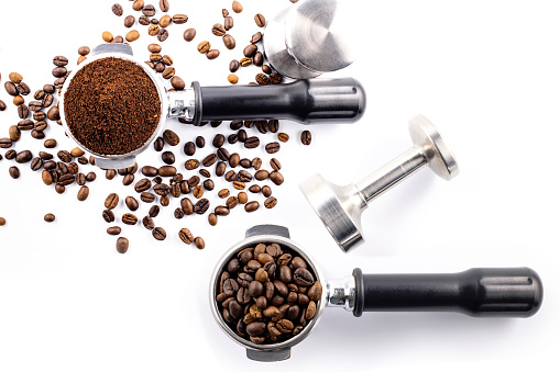 Brown roasted coffee beans and coffee powder on the potta filter isolated on white background.