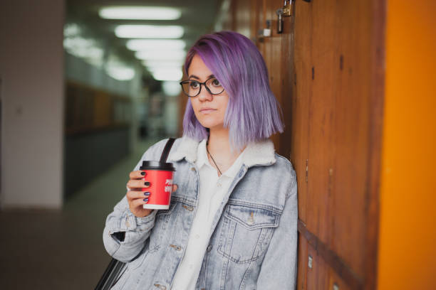 Art school student Young attractive women with purple hair in denim jacket standing in the hall and purple hair stock pictures, royalty-free photos & images