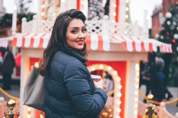 Beautiful young woman in winter clothes looking in frame in christmas market in the afternoon.