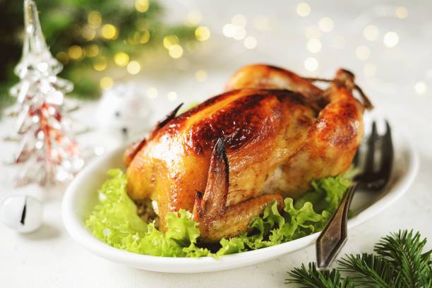 istock Roasted whole chicken on lettuce leaves. Christmas light background. 1195764557