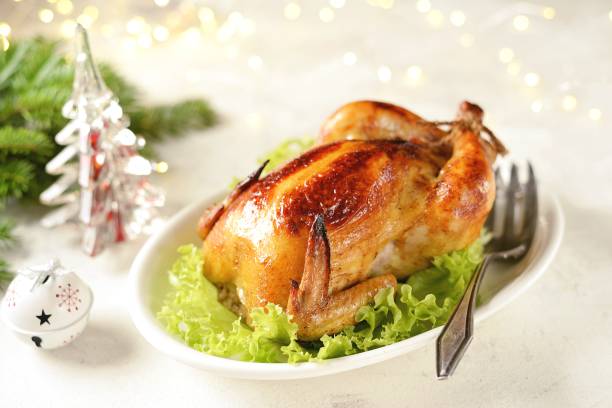 istock Roasted whole chicken on lettuce leaves. Christmas light background. 1195764558