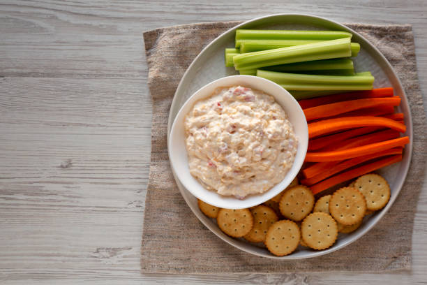 istock Homemade Pimento Cheese Dip with carrots, celery and crackers over white wooden surface. Flat lay, overhead, from above. Copy space. 1195769764