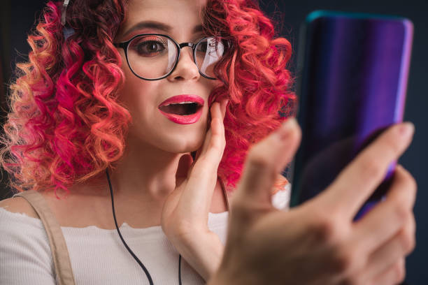 istock Young woman with bright red hair. Smartphone. Shock content. 1195770889