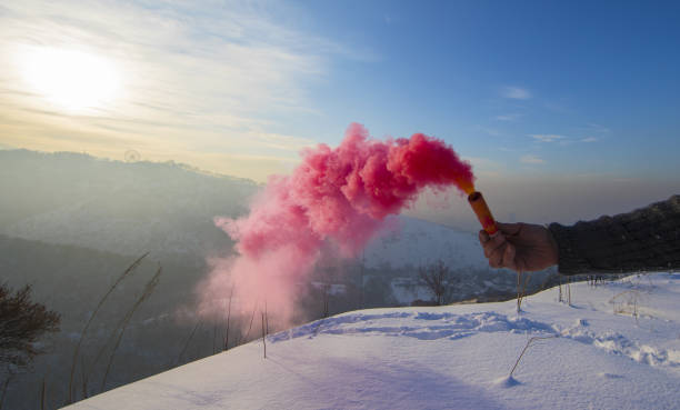 istock smoke bomb in hand with red smoke in winter mountains 1195772739